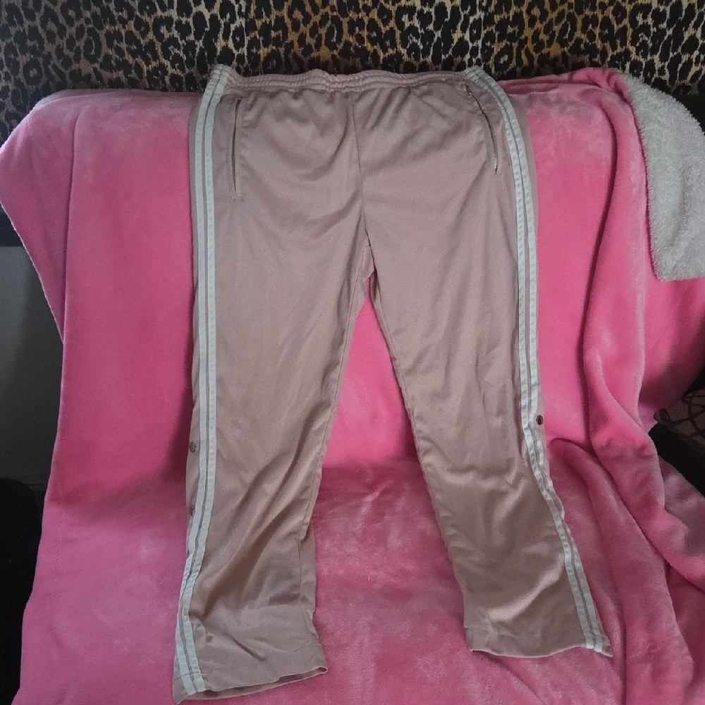 Women's track pants that has buttons on the legs and zippers for pockets.